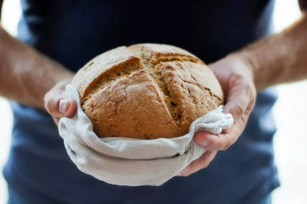 a man holding a loaf of bread, representative of the daily bread God offers us through his Word