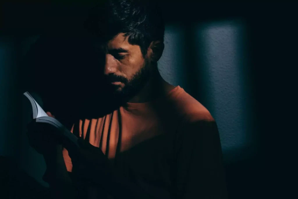 a man in the dark reading a book, representing the persecuted church