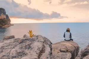 a man sitting on a cliff thinking about serving others